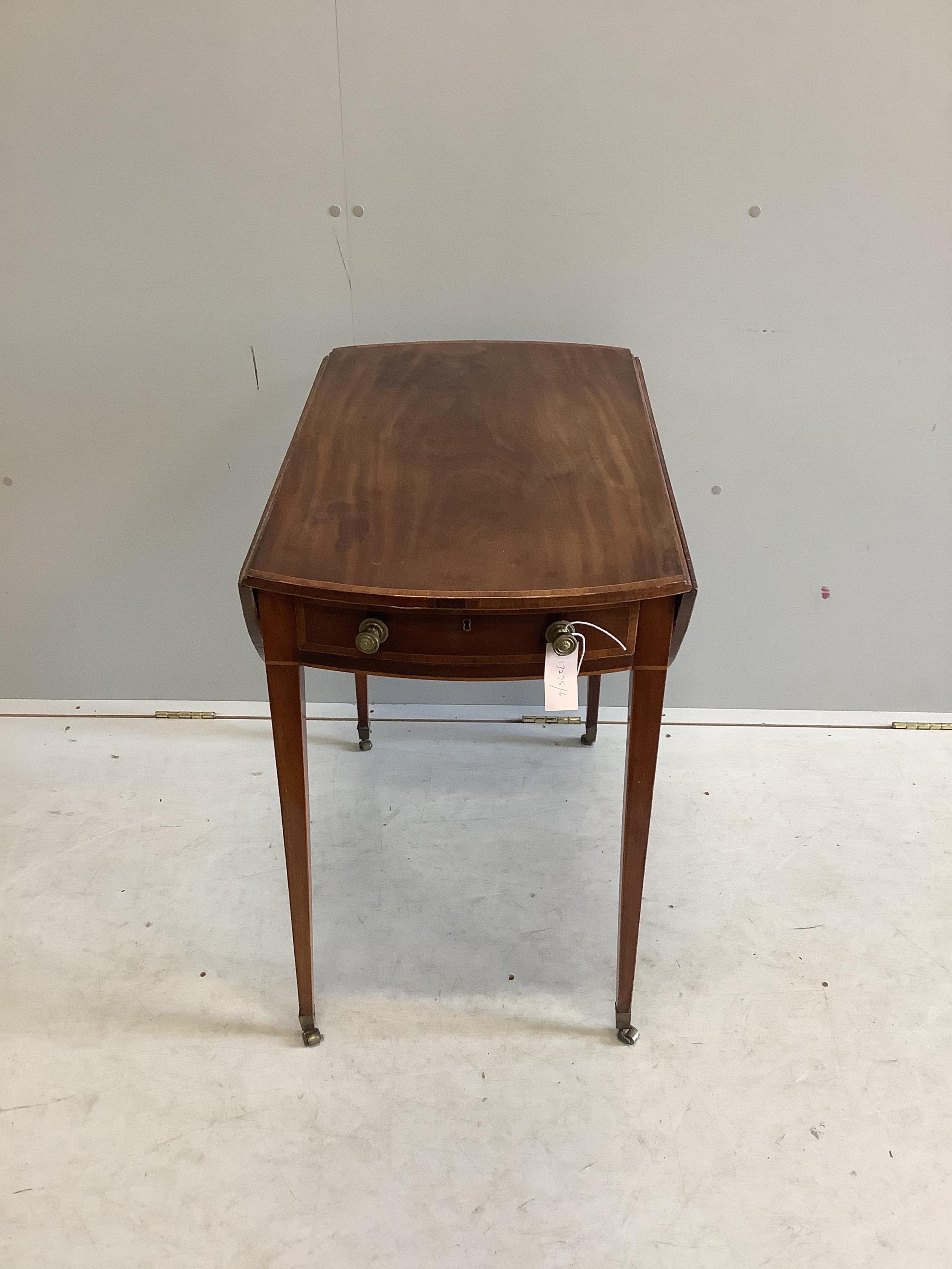 A late Georgian oval banded mahogany Pembroke table on square tapering legs on brass castors, width 46cm, depth 74cm, height 72cm. Condition - fair